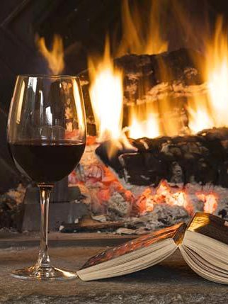 Glass of wine and book by fireplace