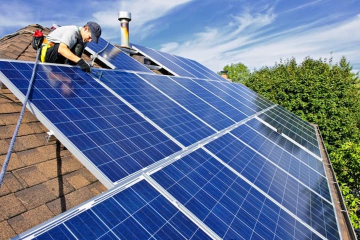 man installing solar panels on the roof of the house