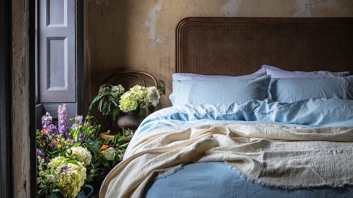 bed with blue sheets and flowers on the side
