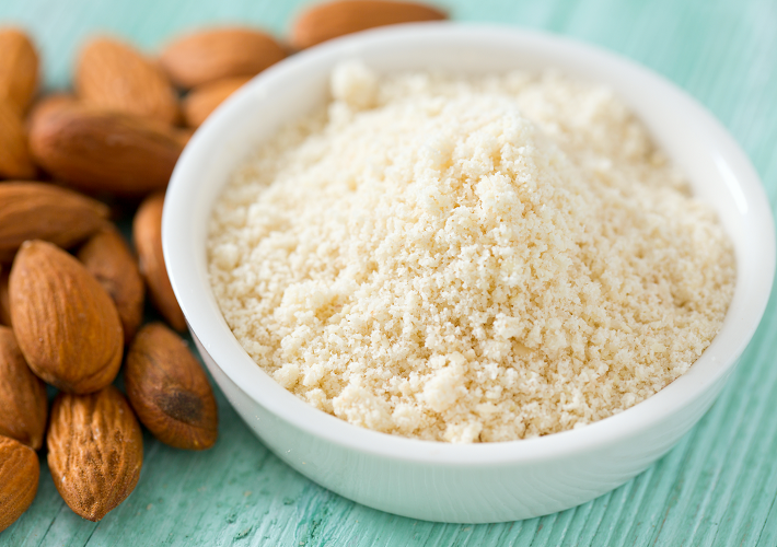 almond flour in white bowl on table with almonds