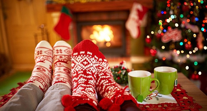people wearing Christmas socks on table next to tea cups.  