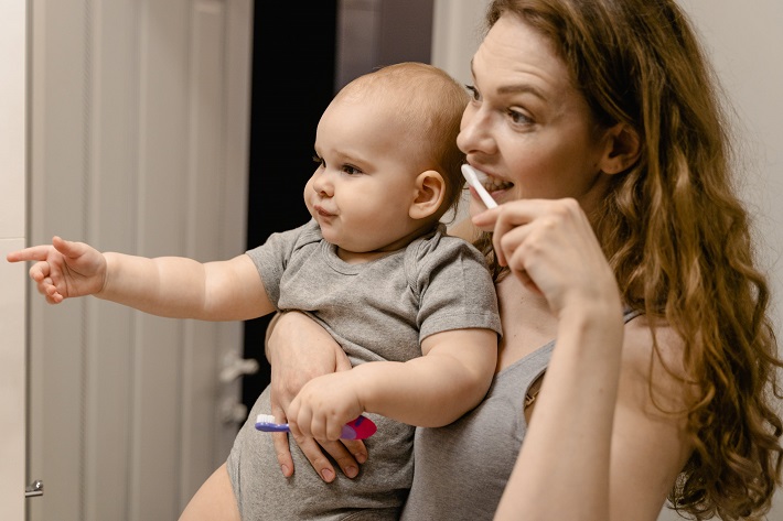 picture of a baby in the hands of a woman washing teeth