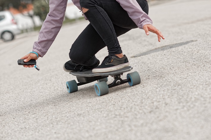 woman riding an electric skateboard with grey wheels 
