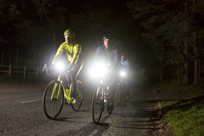 picture of people riding a bike on a night-time with flashlight 