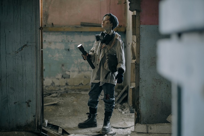 picture of a kid in a ruin building walking with a flashlight