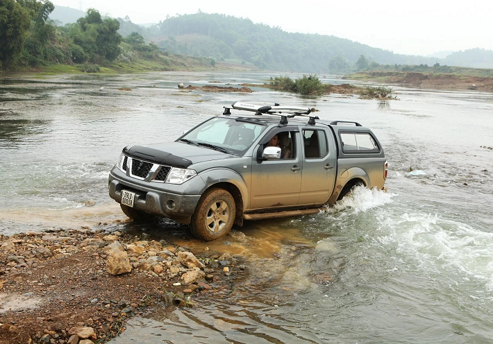 Silver Nissan Navara D40 driven in river in nature