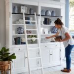 woman decorating Hampton bookshelf