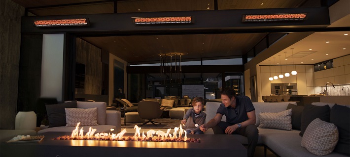 father and son warm themselves on a heater