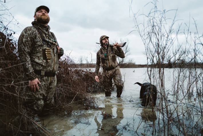 two men standing in the water wearing sitka hunting gear