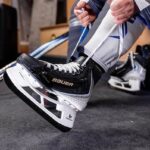 man putting on Bauer Vapor hockey skates