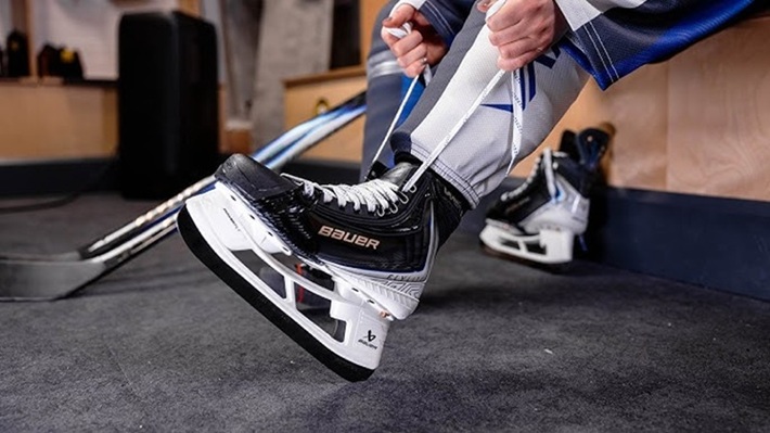 man putting on Bauer Vapor hockey skates
